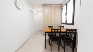 Un pasillo con una mesa de comedor de madera y sillas, un reloj en la pared y una puerta corredera.