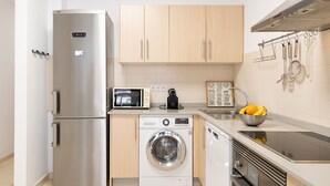 Cocina compacta con refrigerador de acero inoxidable, microondas, lavadora y pileta con frutero.