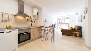 Una cocina moderna con horno integrado, extractor de acero inoxidable y un comedor con mesa y sillas.