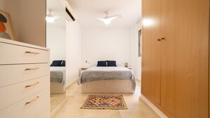 Un dormitorio con cama, mesitas de noche, armario y ventilador de techo.
