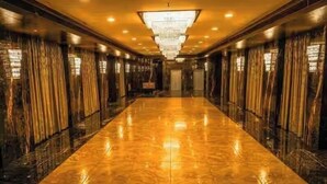 A long, polished corridor with a reflective floor, flanked by curtains and a large chandelier. - Shelter Suites (Formerly known as Fisco The Hub Link) (Mumbai)