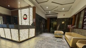 A hotel reception area with a modern design, featuring a reception desk, seating area, and marble flooring. - Shelter Suites (Formerly known as Fisco The Hub Link) (Mumbai)
