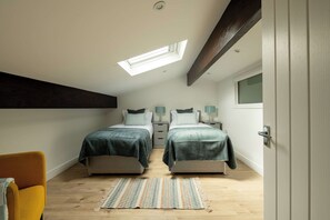 A bedroom with two beds, a skylight, a window, and a door.