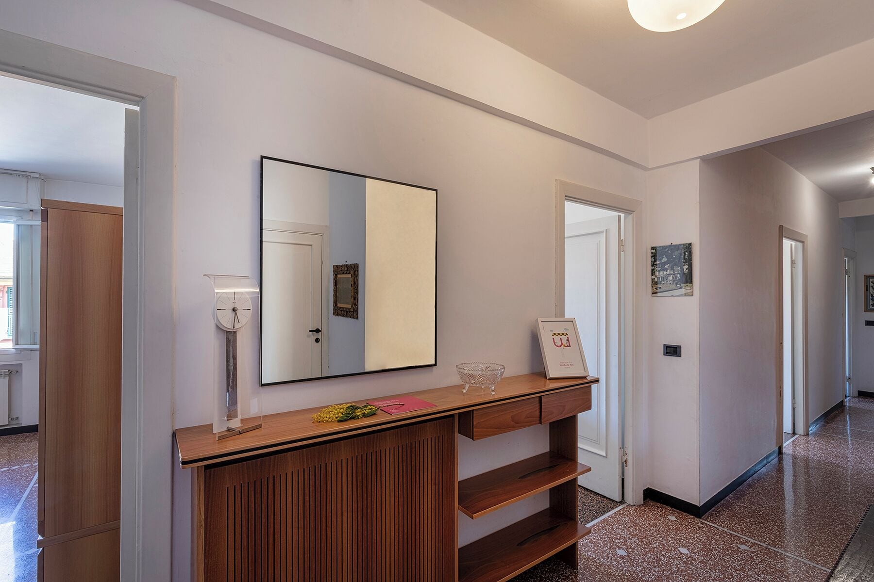 A hallway with a wooden console table, a mirror, and framed pictures on the wall.