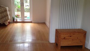 Una stanza con pavimento in legno, una panca, una porta che dà sull'esterno e un lampadario.