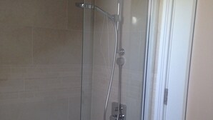 Un angolo doccia chiuso con vetro, una vasca, pareti piastrellate e una porta.