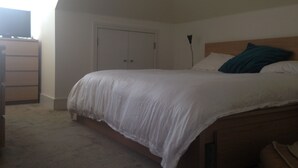 Una camera da letto con un letto, una cassettiera e una porta.