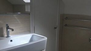 Un bagno moderno con lavandino bianco, uno specchio e una zona doccia.
