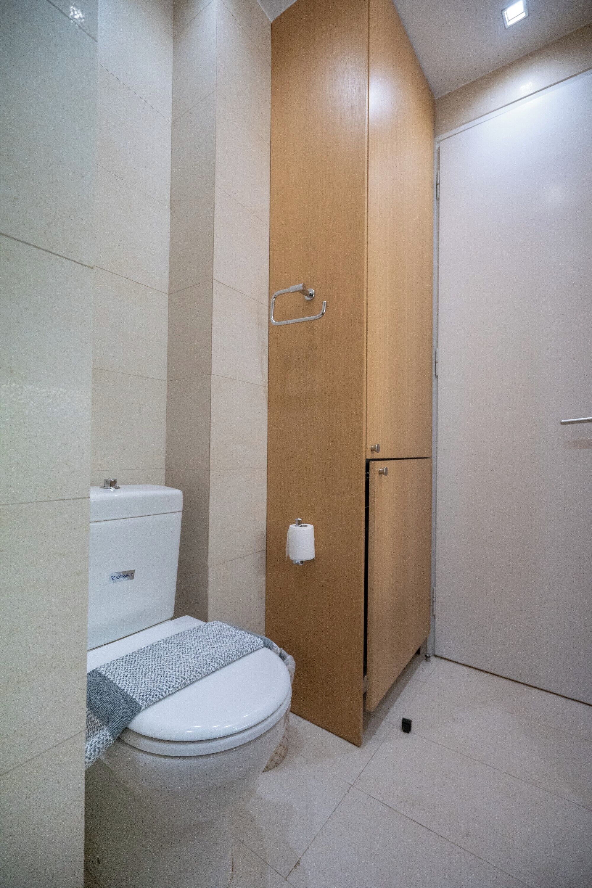 Ein Badezimmer mit Toilette, einem Holzschrank und einer weißen Tür.