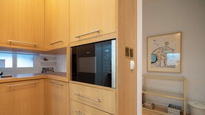 A modern kitchen with wooden cabinets, a built-in oven, and a small window.