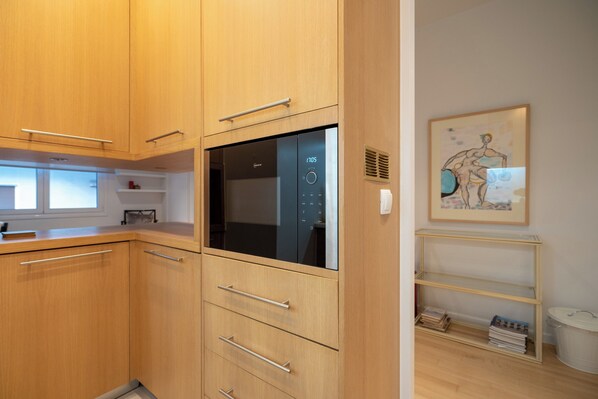 Una cocina moderna con armarios de madera, horno empotrado y un ventanal.