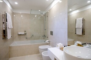 Een moderne badkamer met een douchecabine van glas, een vrijstaand bad, een toilet en een wastafelmeubel met een ruime wastafel.