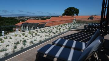 A rooftop terrace with lounge chairs and a view of the cityscape.