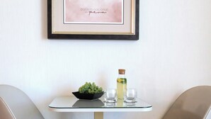 A dining area with two chairs, a table, a framed picture, a bowl of grapes, and a bottle of drink. - Quinta Da Maquia Hotel (Sintra)