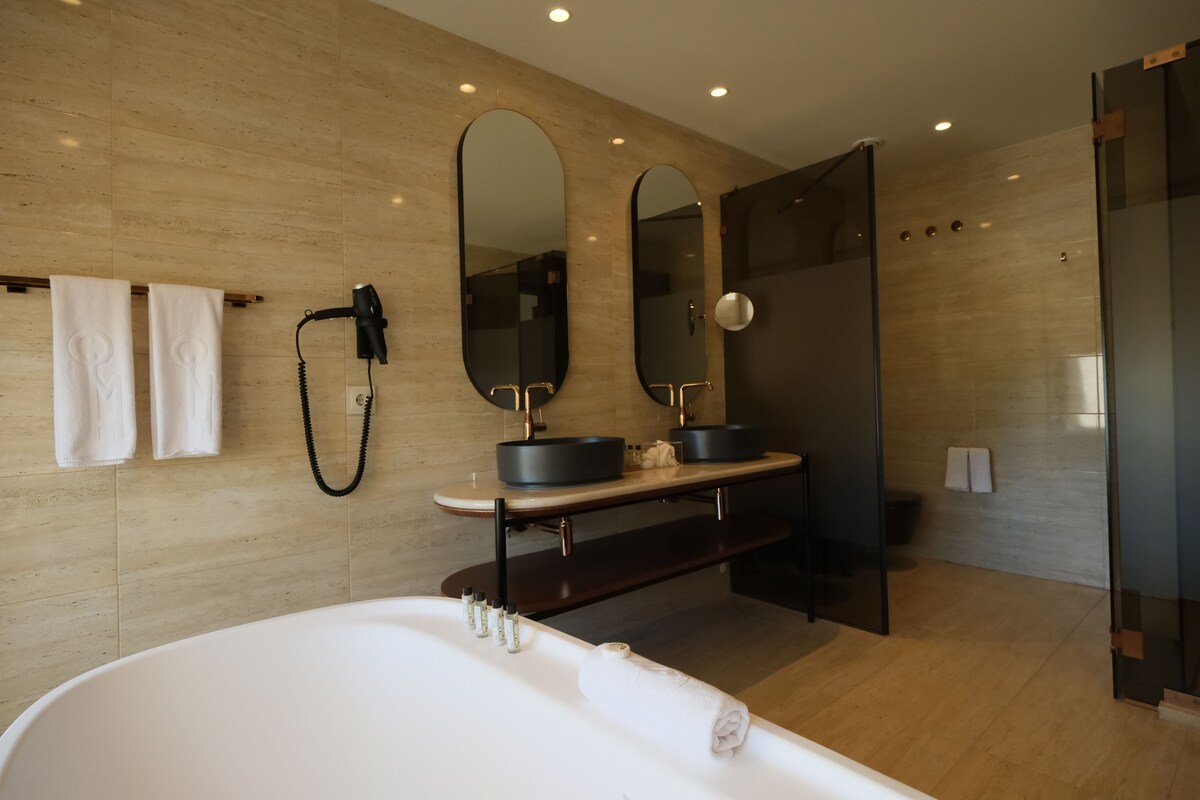 Une salle de bain moderne avec une baignoire sur pieds, deux miroirs, un meuble-lavabo et une cabine de douche en verre.