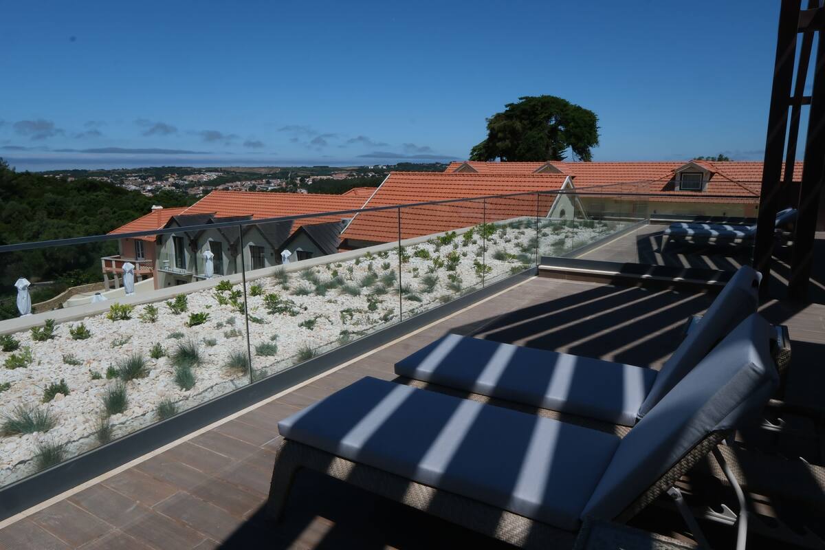 Eine Dachterrasse mit Liegestühlen und Blick auf die Stadt.