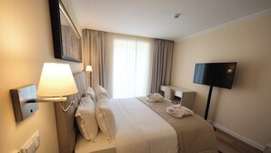 A hotel room with a large bed, a bedside table, a TV, and a window with curtains. - Quinta Da Maquia Hotel (Sintra)