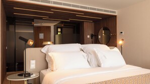 A modern hotel room with a neatly made bed, a round mirror, and two bedside lamps. - Quinta Da Maquia Hotel (Sintra)