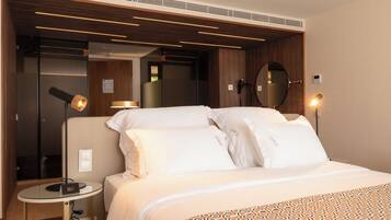 Una habitación de hotel moderna con una cama bien hecha, un espejo redondo y dos lámparas de noche.