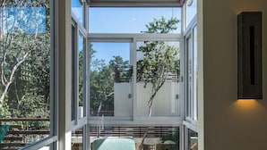 Un interior moderno con ventanas amplias, una silla verde y una mesa de centro de madera.