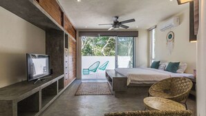 Un dormitorio moderno con cama, televisor, ventilador de techo y vista al exterior.