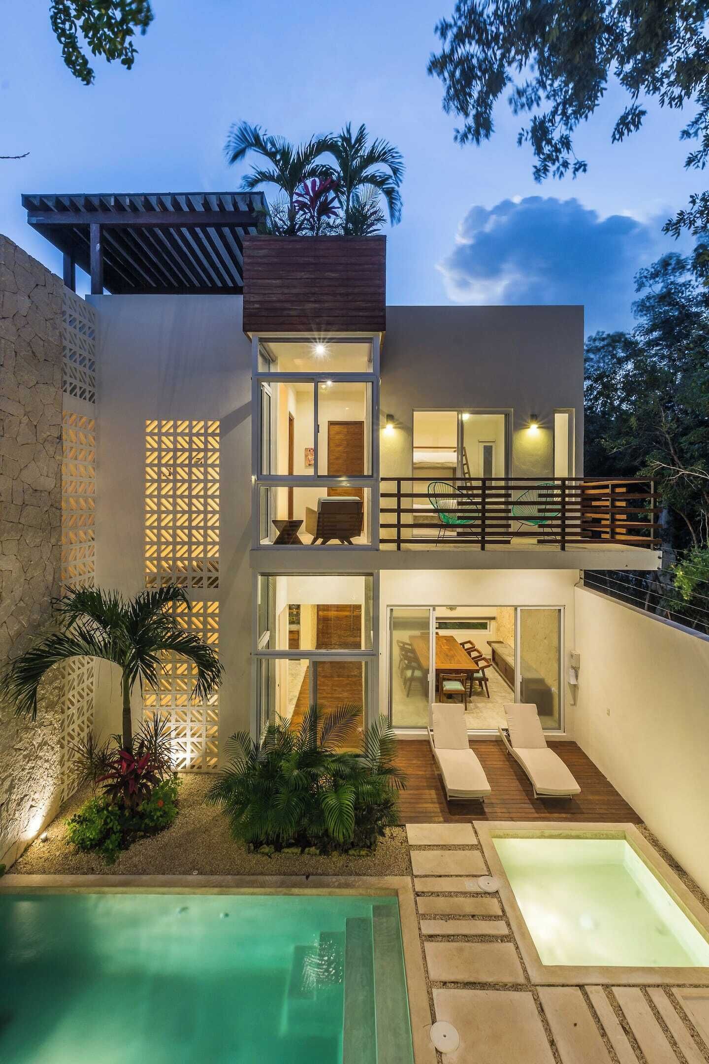 Une maison moderne à deux étages dotée d’une piscine, d’un espace salon extérieur et d’un balcon.