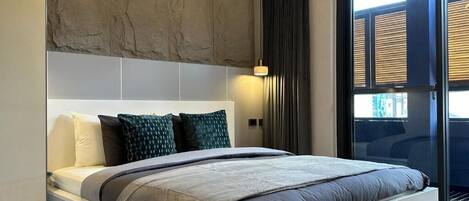 Un dormitorio moderno con una cama grande, una pared de acento de piedra y vistas a través de un ventanal.