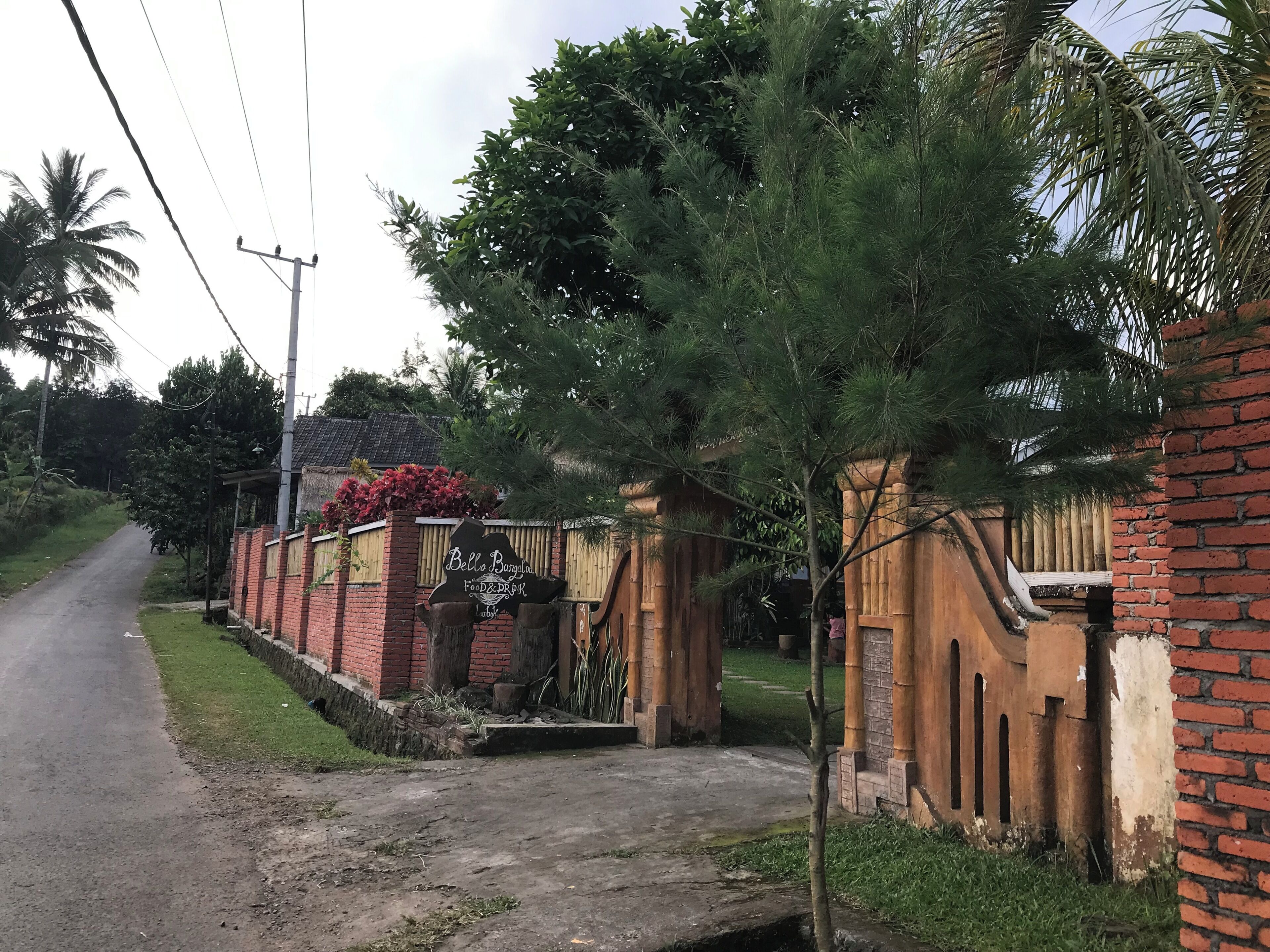 Un barrio residencial con una casa de ladrillo, un camino de entrada pavimentado y una valla de madera.