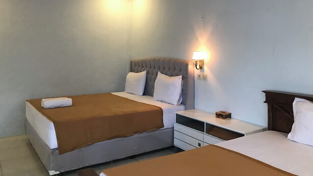 Ein Hotelzimmer mit zwei Betten, einem Nachttisch, einer Lampe und einer Deckenleuchte.