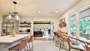 A modern kitchen with a central island, bar stools, and a view of the outdoors. - Biltmore Forest Retreat! Sauna Hot tub Game Rm (Asheville)