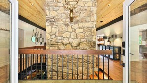 A modern interior with a stone wall, wooden ceiling, and a staircase with metal railings. - Biltmore Forest Retreat! Sauna Hot tub Game Rm (Asheville)
