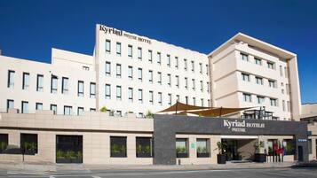 A modern hotel building with a prominent sign reading "Kyriad Prestige Hotel".