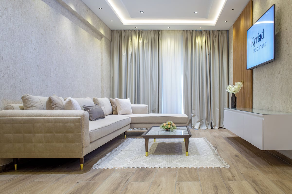 Ein modernes Wohnzimmer mit einer Couch, einem Couchtisch und einem an der Wand montierten Flachbildfernseher.