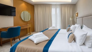 Een hotelkamer met een groot bed, een bureau, een stoel, een televisie en een spiegel.