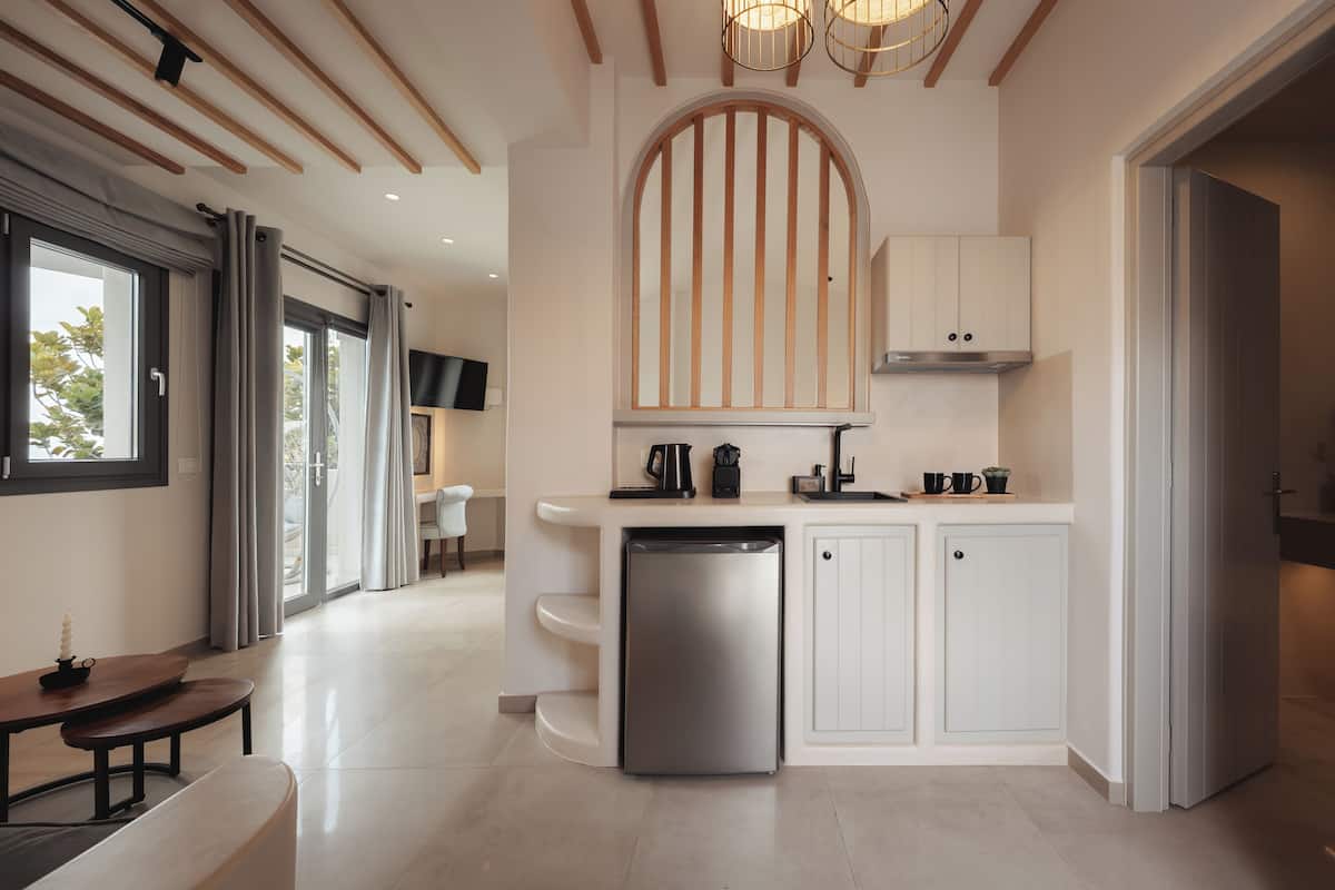 Una cocina moderna con lavavajillas, armarios blancos y un ventanal grande.