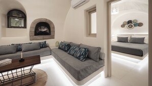 En moderne stue med pejs, sofa, sofabord og seng med ovenlys.