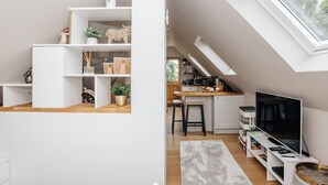 Un espace de vie compact doté d’une cuisine en mezzanine, d’étagères intégrées et d’un téléviseur.