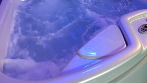 Ein Whirlpool mit Bedienfeld und einer Holzverkleidung darüber.
