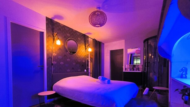 Ein modernes Schlafzimmer mit einem großen Bett, einem kleinen Nachttisch und einem Spiegel an der Wand.