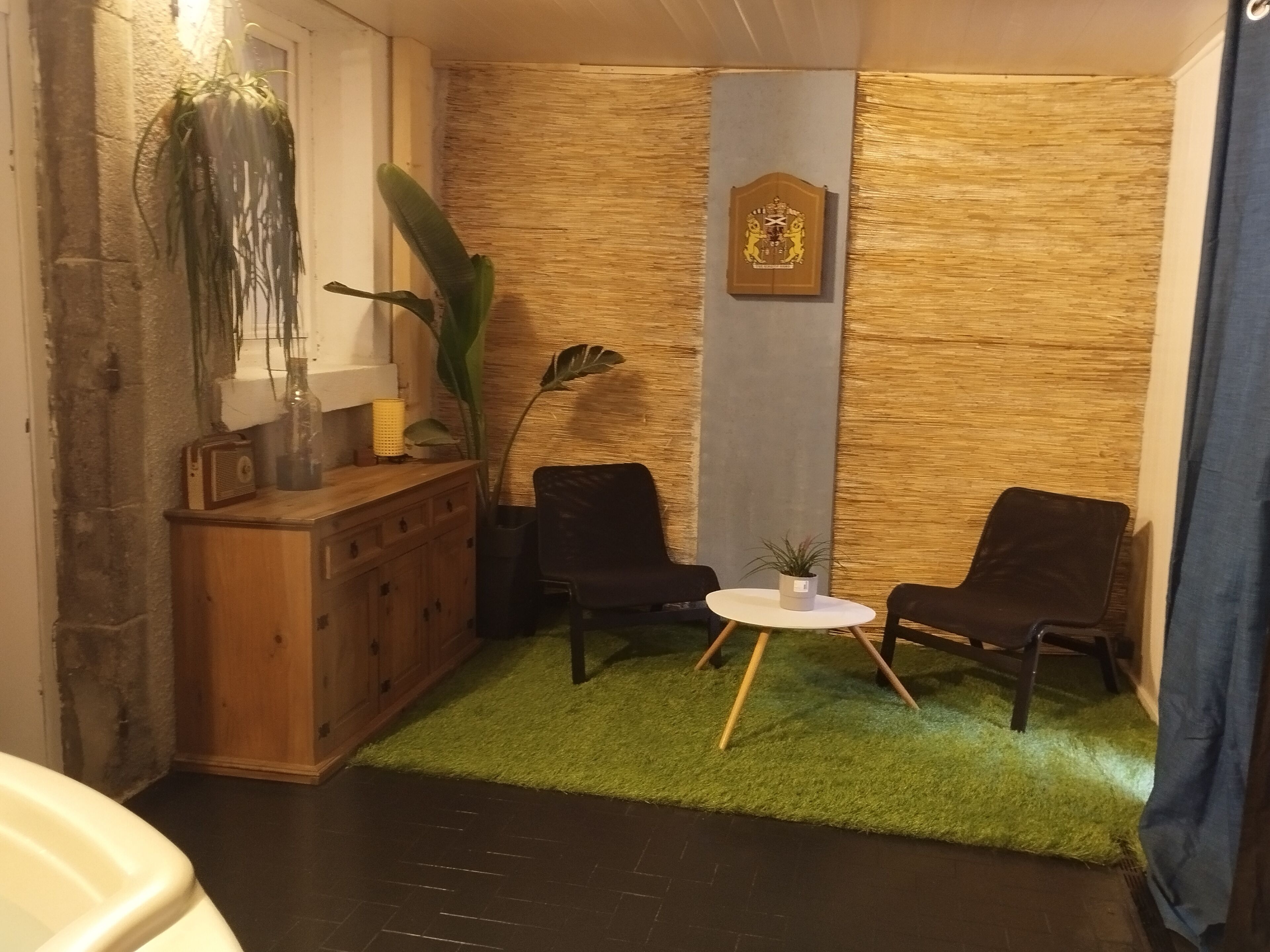 Eine gemütliche Ecke mit einem Holzschrank, zwei Stühlen, einem kleinen Tisch und einer Wanddekoration.