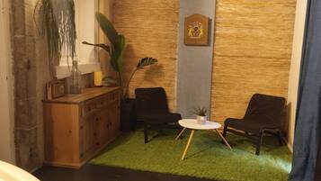 Eine gemütliche Ecke mit einem Holzschrank, zwei Stühlen, einem kleinen Tisch und einer Wanddekoration.