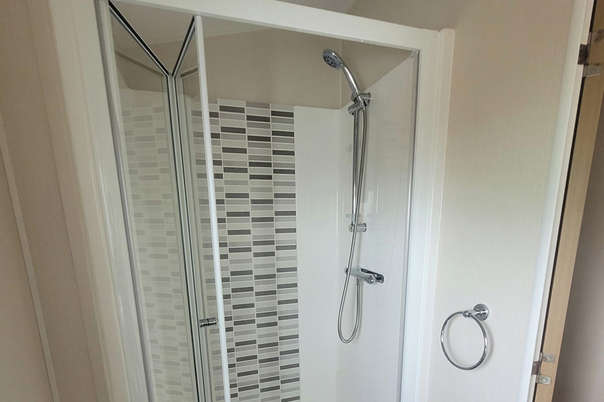Una doccia con porta in vetro e porta asciugamani.