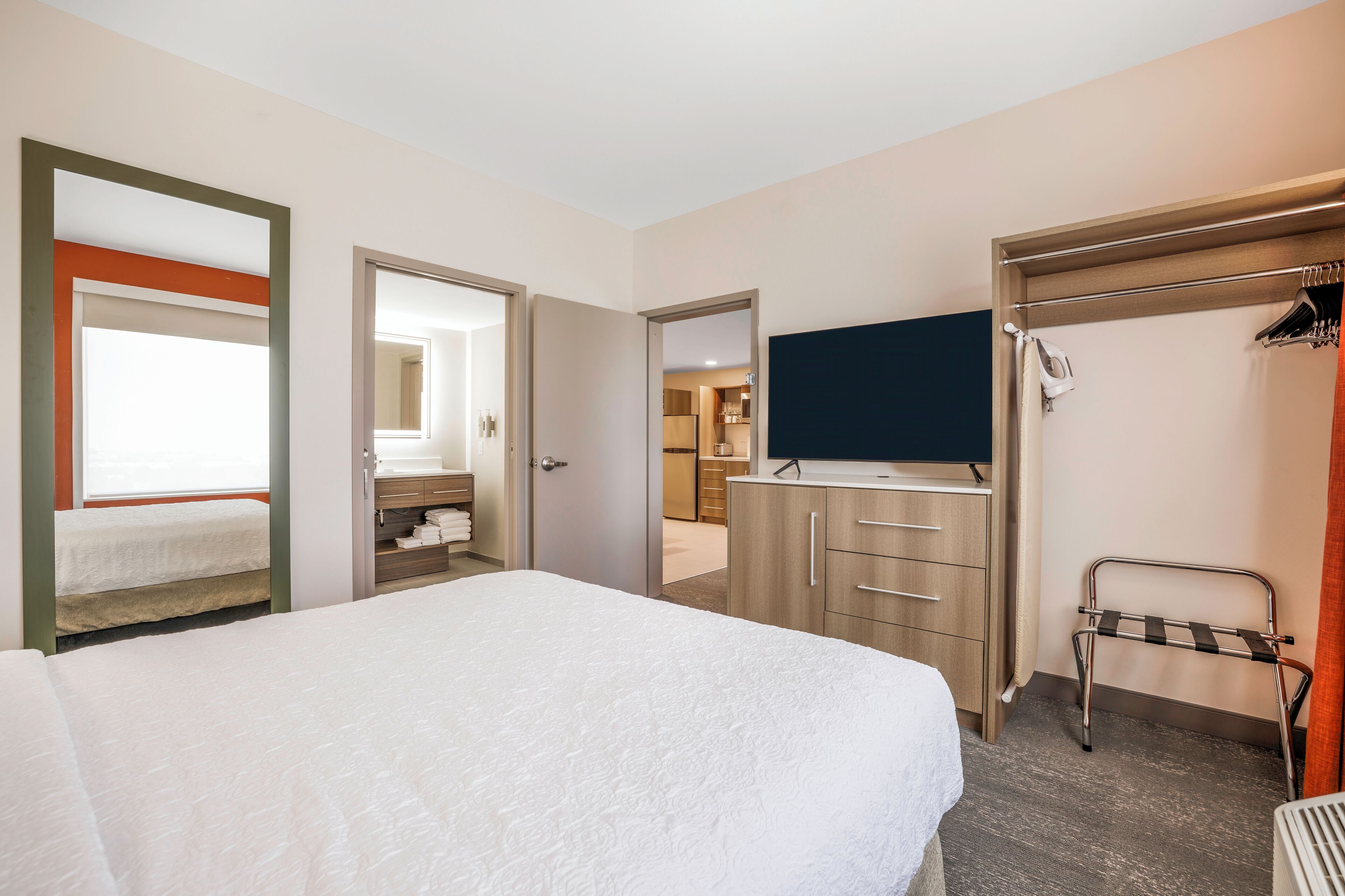 A hotel room with a large bed, a TV, a wardrobe, and a bathroom visible through an open door.