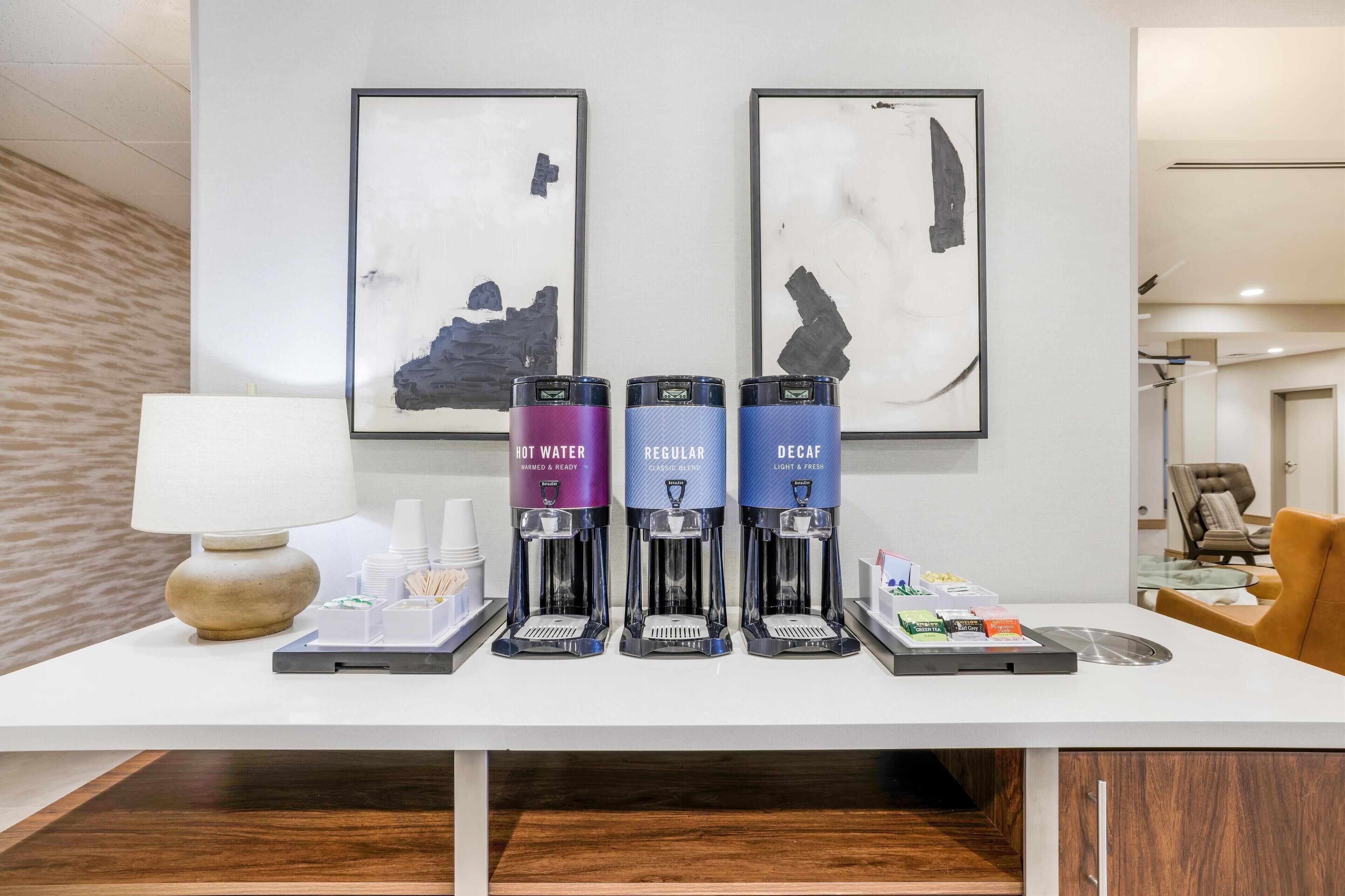 A coffee station with three coffee makers labeled "HOT WATER," "REGULAR," and "DECAF."