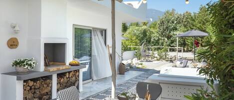 Un patio con mesa lista para comer, una parrilla y una zona de estar con una silla colgante.