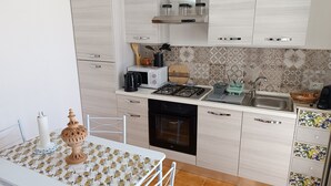 Una cocina moderna con armarios blancos, estufa a gas, microondas y un lavamanos.