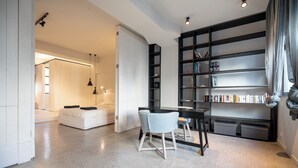En moderne stue med en hvid sofa, et spisebord med to stole og et stort reol fyldt med bøger.