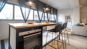Et moderne køkken med indbygget ovn, en træbordplade og en bar med to stole.