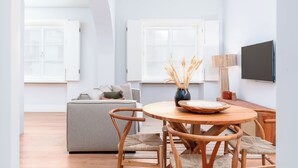 Una sala de estar moderna con una mesa redonda de madera, un sofá gris y sillas de madera.