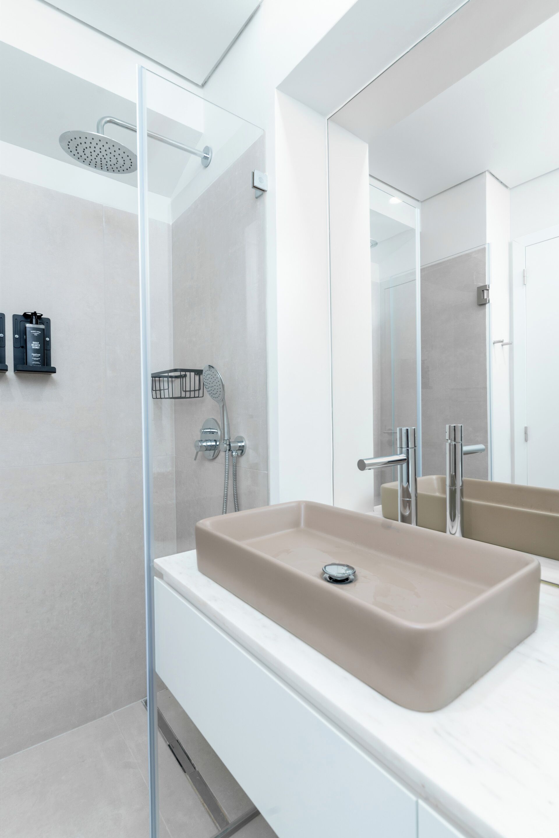 A modern bathroom with a glass shower enclosure, a beige sink, and a large mirror.